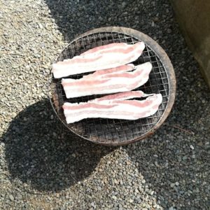 七輪で豚肉を焼いている写真